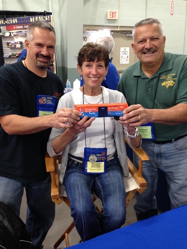 Being held up by train enthusiasts is the Lionel Collectors Club of Americas Switching Tracks Traveling boxcar LCCAs Switching Tracks Traveling boxcar is held up by enthusiasts