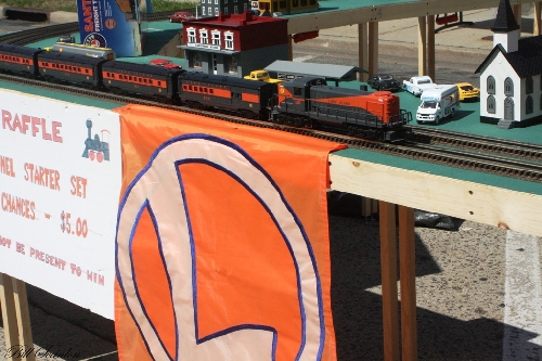 Long Island passenger train set rolls down the track at the Bellmore Street fair displaying Lionel Lines Passenger Train Set on the The Lionel Club Ambassador TMB Model Train Club modular layout The Lionel Club Ambassador TMB Model Train Club modular layout runs the Long Island passenger train set down the track at the Bellmore Street fair on the