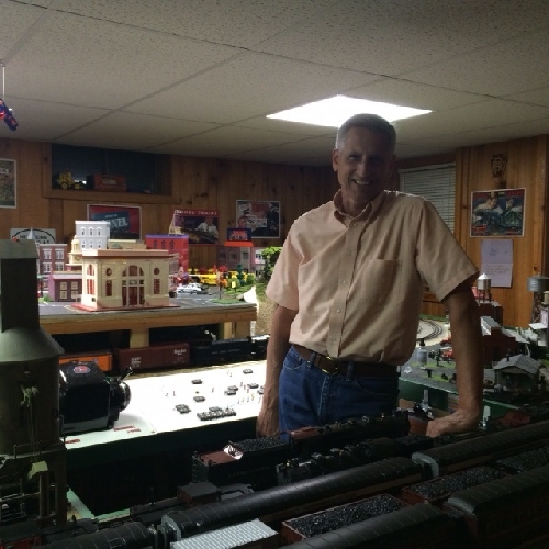 Grove Roys stand in front of his extended model train layout and shows off his love of Lionel Trains